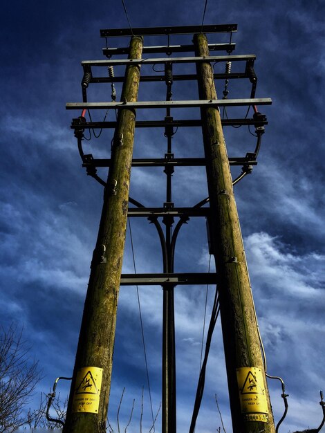 Low angle view of electricity pylon against cloudy sky