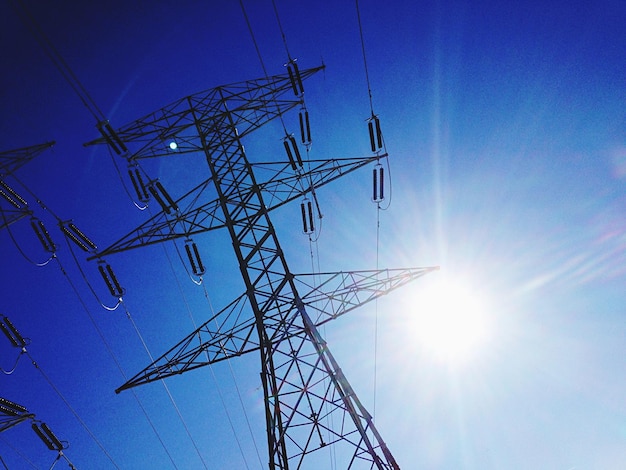 Low angle view of electricity pylon against sky during sunny day