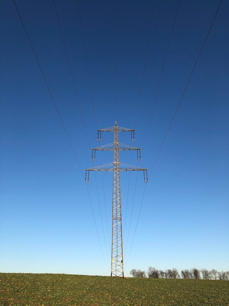 明るい空を背景にフィールドの電力ピロンの低角度の視点