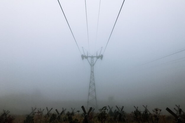 Low angle view of electricity pylon on field against sky