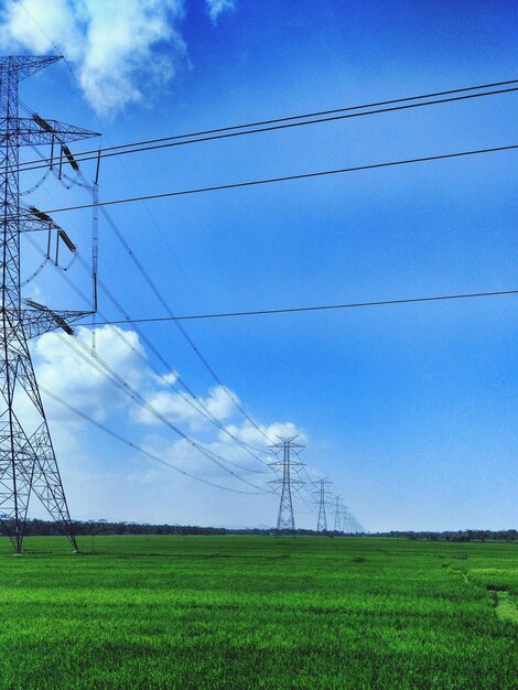 Low angle view of electricity pylon on field against sky