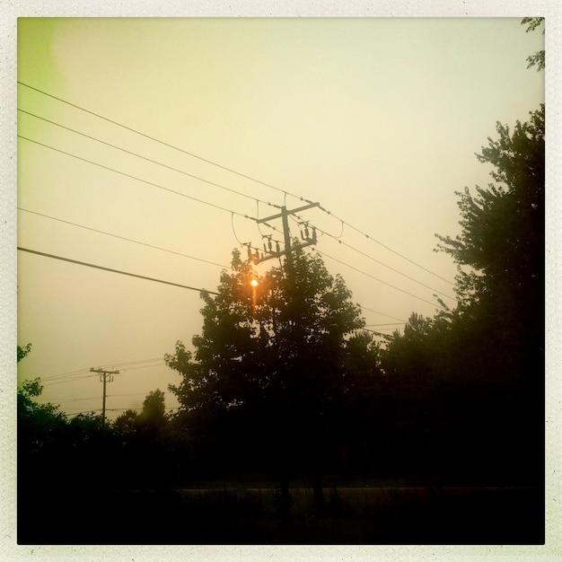 Low angle view of electricity pylon during sunset