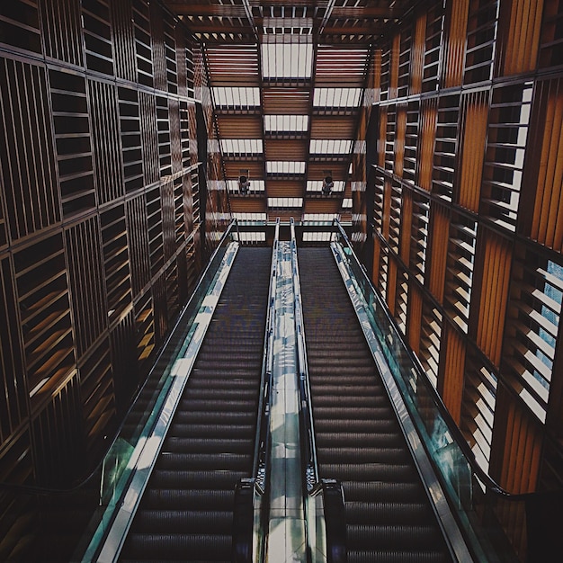 Photo low angle view of escalators along built structures