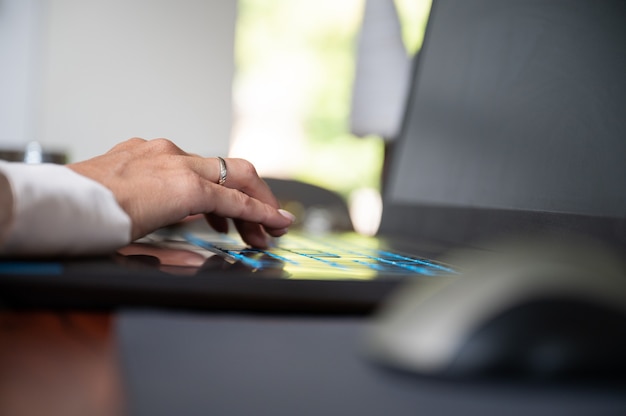 Low angle view of a female hand typing on laptop computer.