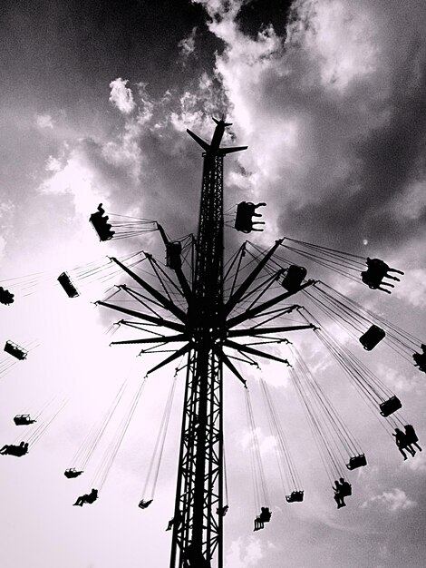 Low angle view of ferris wheel against cloudy sky