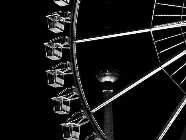 Photo low angle view of ferris wheel and fernsehturm tower at night