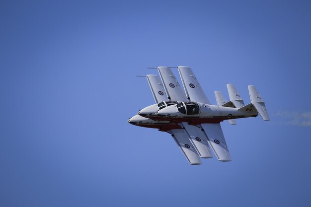 Foto vista a bassa angolazione di un aereo da combattimento che vola contro un cielo blu limpido