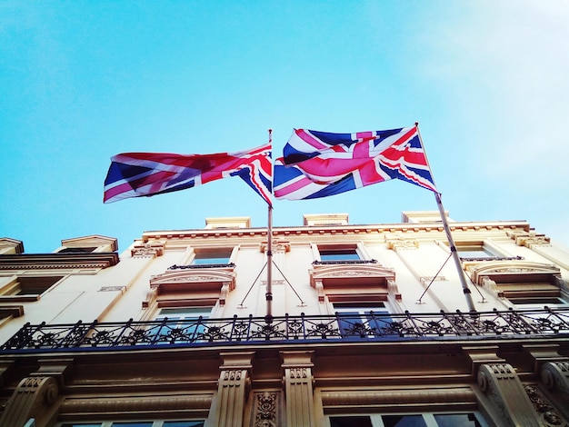 Low angle view of flag against building against blue sky