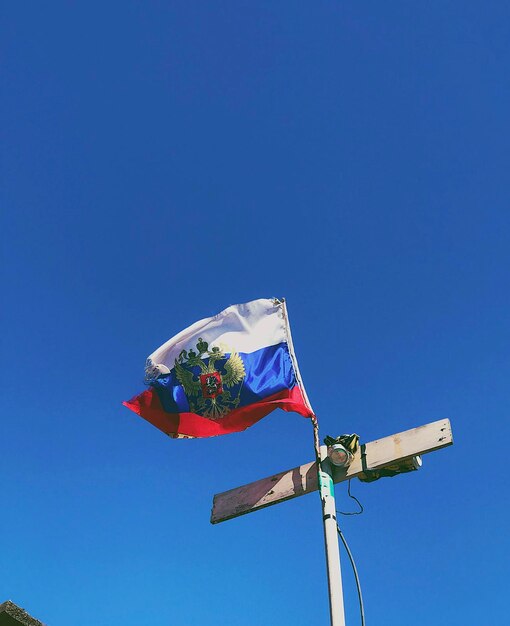 Low angle view of flag against clear blue sky