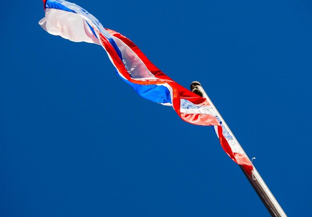 Low angle view of flag against clear blue sky