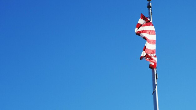 Low angle view of flag against clear blue sky