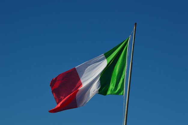 Low angle view of flag against clear blue sky