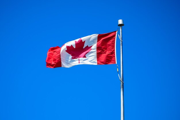 Low angle view of flag against clear blue sky