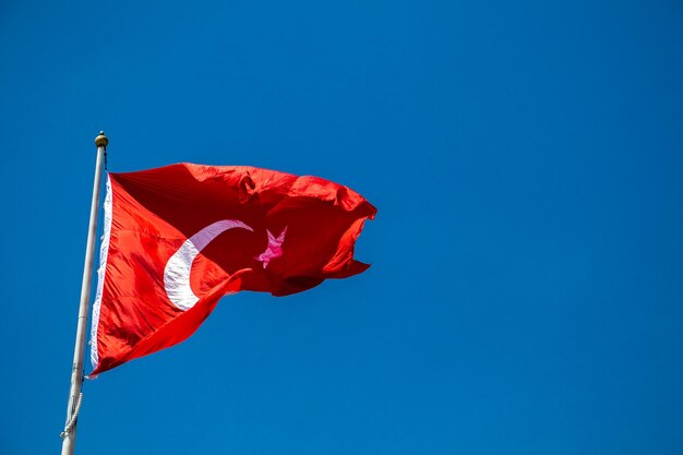 Low angle view of flag against clear blue sky