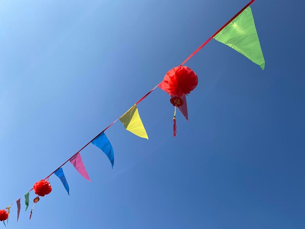 Low angle view of flags against clear blue sky