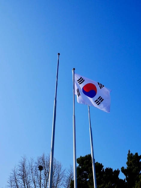 Low angle view of flags against clear blue sky