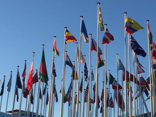 Low angle view of flags against clear blue sky