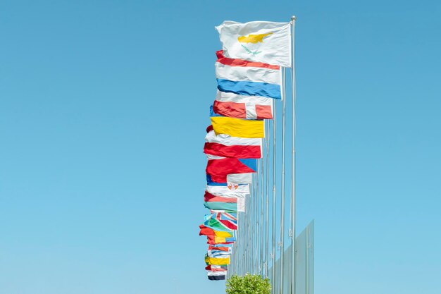 Low angle view of flags of various UN members fluttering on wind against sky