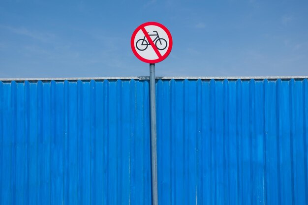 Low angle view of forbidden sign on blue wall against sky during sunny day