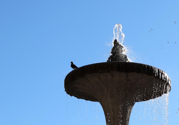 Low angle view of fountain against clear blue sky