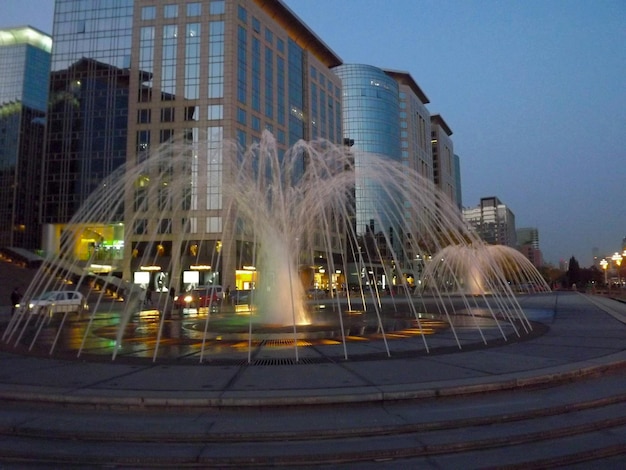 Photo low angle view of fountain and buildings in city at dusk