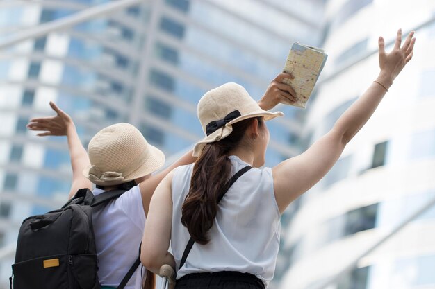 Photo low angle view of friends with arms raised standing against building in city