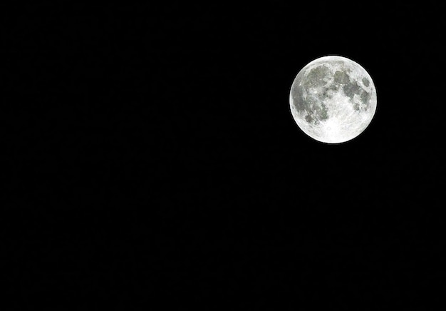 Foto vista a basso angolo della luna piena contro un cielo limpido di notte