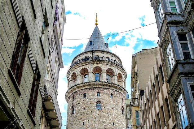 Low angle view of galata tower amidst buildings against sky
