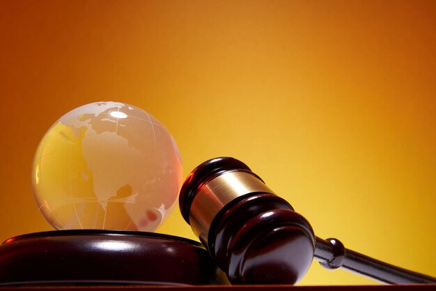 Photo low angle view of gavel hammer and glass globe against orange background