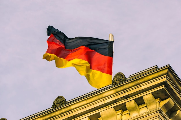 하늘을 배경으로 건물에 독일 국기가 낮은 각도에서 보입니다.
