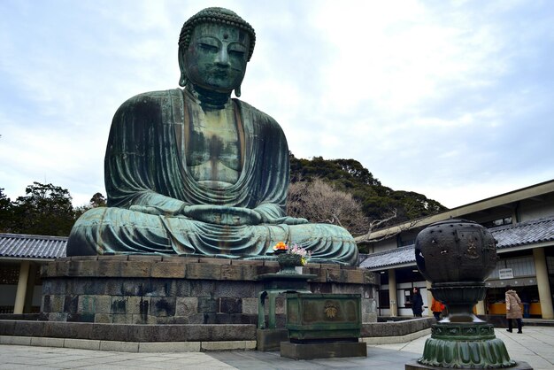 Photo low angle view of giant buddha statue at kotoku-in temple against sky