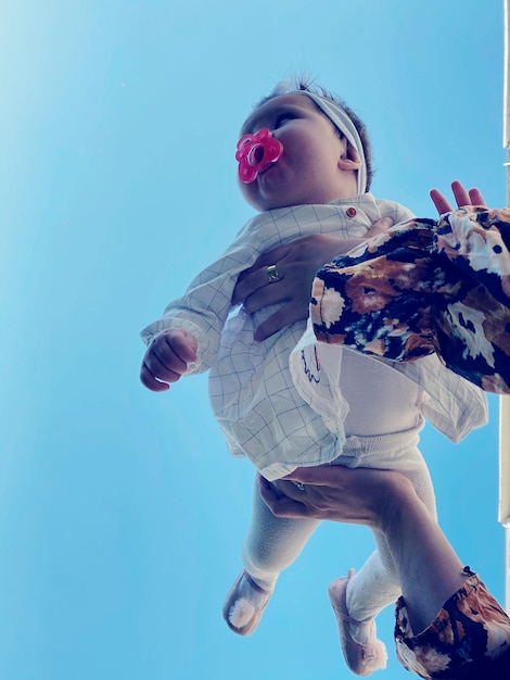 Photo low angle view of girl against blue sky