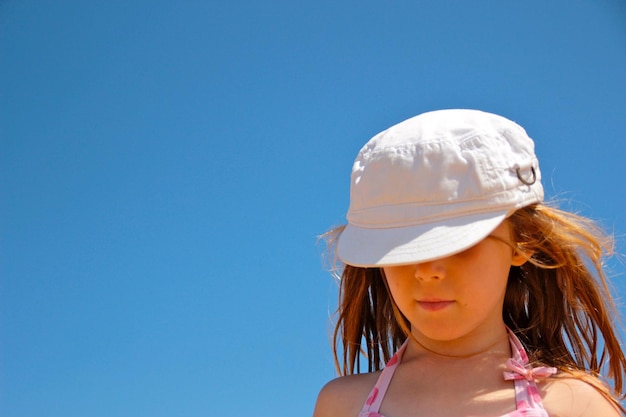 Low angle view of girl against clear blue sky