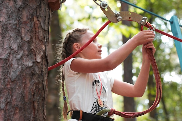 숲 에서 로프 에 안전 허니 를 부착 하고 있는 소녀 의 낮은 각도 의 모습