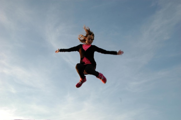 Photo low angle view of a girl jumping against the sky