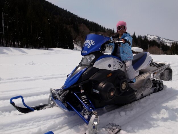 Foto vista a bassa angolazione di una ragazza che guida una moto sulla neve