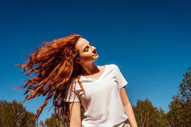 Foto vista a basso angolo di una ragazza che lancia i capelli contro il cielo