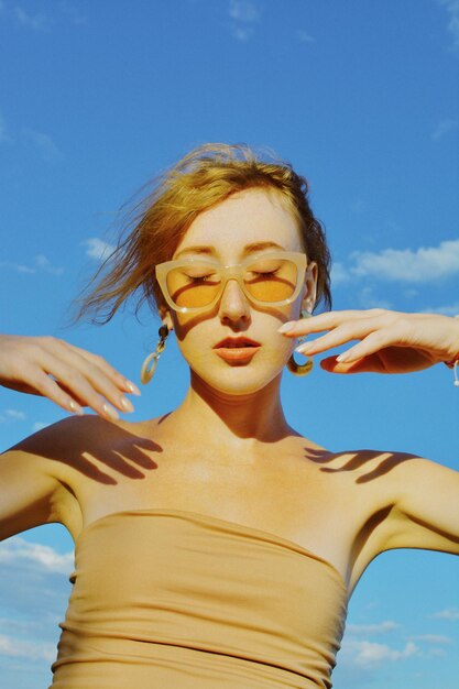 Photo low angle view of girl wearing sunglasses standing against sky