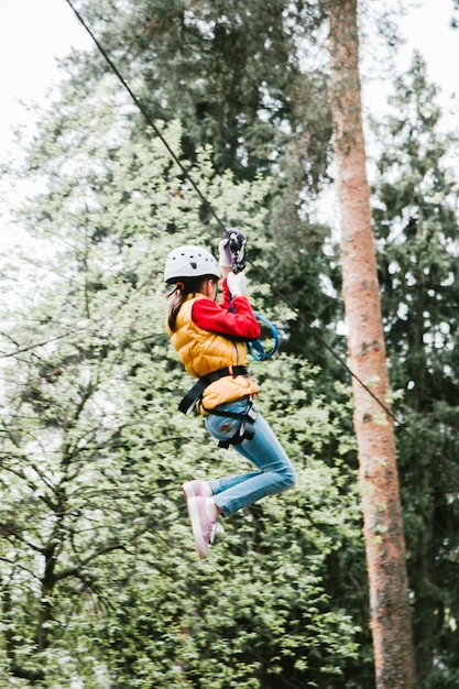 Photo low angle view of girl zip lining in forest