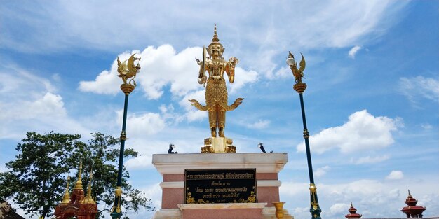 Low angle view of gold statue against sky