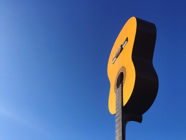 Foto vista a basso angolo della chitarra contro un cielo blu limpido