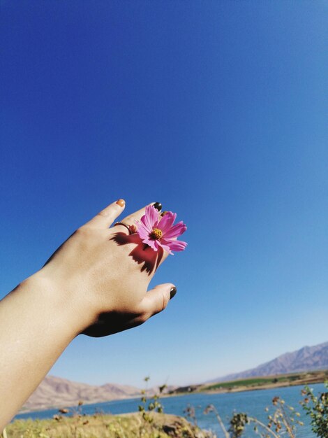 Low angle view of hand against blue sky