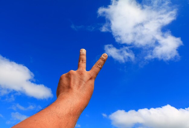 Foto vista a bassa angolazione del gesto della mano contro il cielo blu