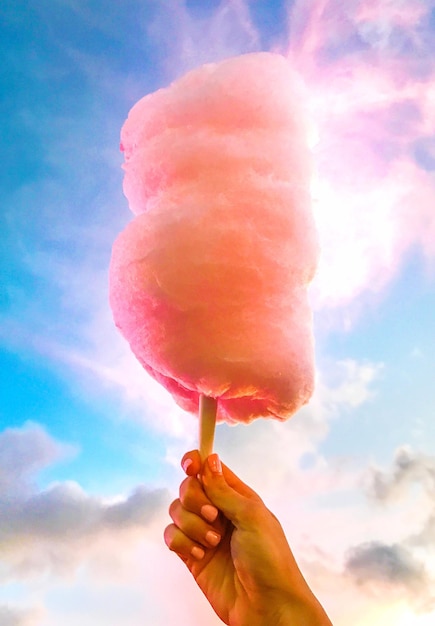 Photo low angle view of hand holding cotton candy against sky