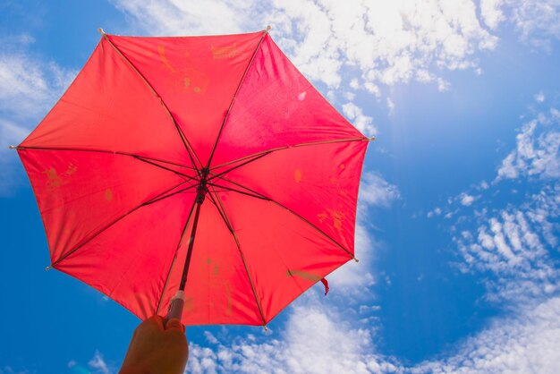 Low angle view of hand holding umbrella against sky