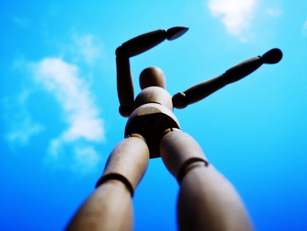 Low angle view of hands against blue sky