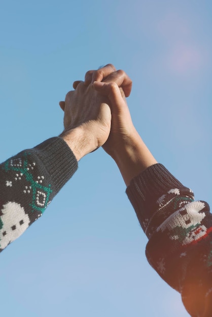 Low angle view of hands clasped against clear sky