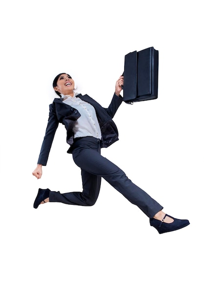 Low angle view of happy businesswoman with bag jumping against white background