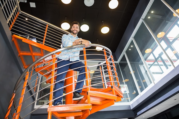 Low angle view of happy male standing on staircase