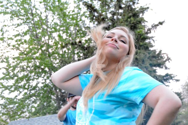 Low angle view of happy young woman dancing against tree